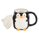 Black mug with penguin design and a white knit hat on a white background