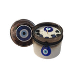 Candle with blue and white evil eye design on top of a white container.