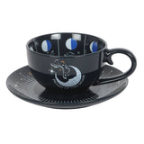 Black cup and saucer set with moon phase design on a white background