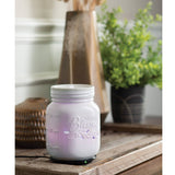 Mason jar-shaped diffuser on a wooden surface with a blurred background