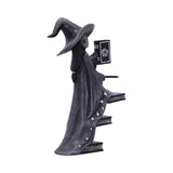Decorative witch figurine holding a book on a white background