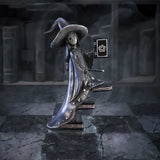 Statue of a witch in a dark, mystical setting with books and a pentacle symbol.