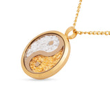 Gold necklace with a yin yang pendant on a white background