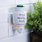 Wall-mounted diffuser with 'live well, laugh often, love much' text next to a plant.
