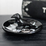 Black ceramic crow on a black dish with a white background