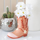 Decorative boot with flowers and a cactus in the background