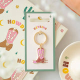 Cowboy boot keychain in packaging with 'Howdy' background