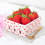 Basket of strawberries with a heart pattern on a white background