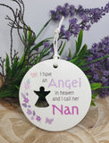 Round ceramic ornament with text and silhouette, surrounded by flowers and greenery