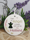 Memorial ornament with text 'I have an angel in heaven and I call him my husband' against a natural background.