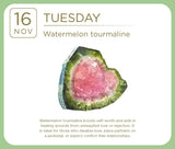 A square card featuring a polished watermelon tourmaline crystal. The card has a white background with a light green border, displaying the date '16 NOV' and the day 'TUESDAY' at the top, with descriptive text about the crystal's healing properties below the central image.