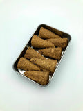 Metal tray with six brown dog treats on a light blue background