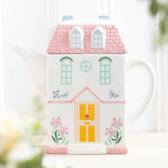 Ceramic mug designed like a house with a pink roof and yellow door, featuring floral patterns.
