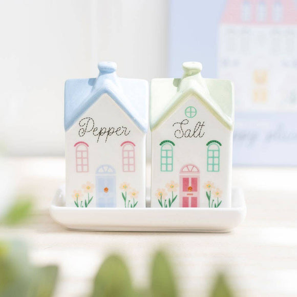 Salt and pepper shakers shaped like houses with colorful doors on a white surface.