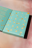 Teal advent calendar with gold numbers and stars on a pink background