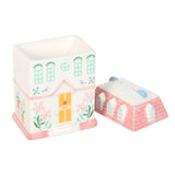 Two house-shaped candles with decorative designs on a white background