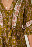 Close-up of a green patterned dress with floral and paisley designs.