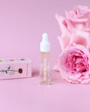 Skincare dropper bottle with pink roses on a pink background