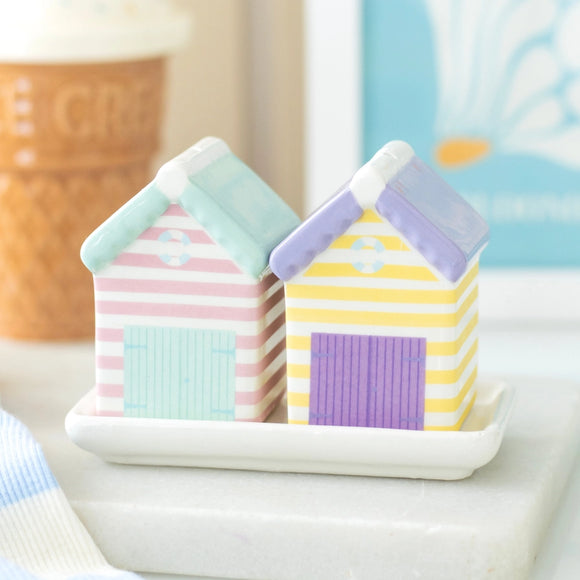 Two small, colorful house-shaped containers on a white surface with a blurred background.