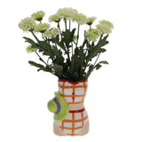 Decorative vase with a checkered pattern and a green watering can design, containing white flowers on a white background.