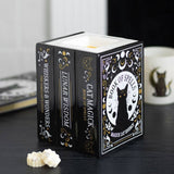 Decorative candle with book design featuring a black cat on a dark surface.