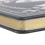 Close-up of a black and gold book with decorative elements on a white background