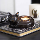 Cat-shaped candle holder with a lit candle on top of a book titled 'Black Cat Energy'.