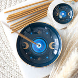 Two blue ceramic incense holders with star and moon designs on a textured surface.