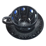 Black ceramic cup and saucer with celestial design on a white background