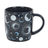 Black mug with celestial design featuring moons, stars, and suns on a white background