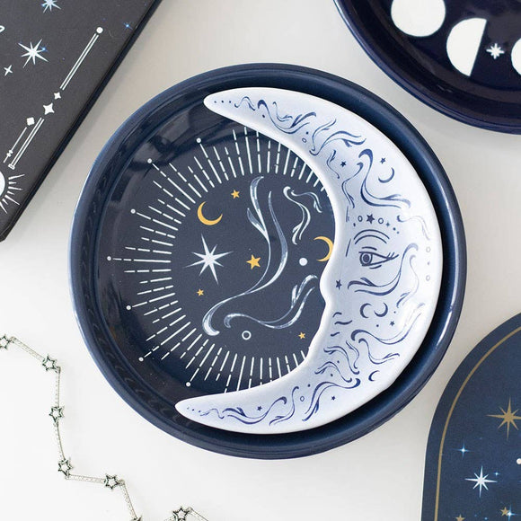 Decorative plate with celestial design featuring moon, stars, and eye on a white surface.