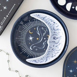 Decorative plate with celestial design featuring moon, stars, and eye on a white surface.
