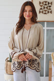 Woman wearing a beige blouse with intricate patterns in a home setting