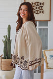 Woman wearing a beige cardigan with floral embroidery in a home setting