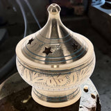 Decorative ceramic incense burner with silver top on a dark surface