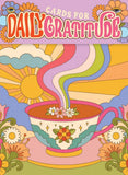 A colorful illustrated card design with the text 'CARDS FOR DAILY GRATITUDE' at the top. The artwork shows a teacup with flowers, rainbow steam, a sun, clouds, and flowers in a retro psychedelic style.