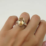 Silver ring with a yellow gemstone on a light gray background