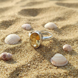 Silver ring with a yellow gemstone on a light gray background