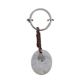 Keychain with round metallic pendant and brown leather strap on a white background