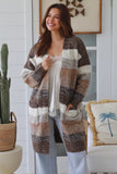 Woman wearing a patterned cardigan in a home setting with decor elements.
