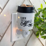 Wall-mounted wax warmer with a coffee-themed mug on a tiled wall.