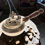 Decorative incense burner with wooden handle on a stone surface
