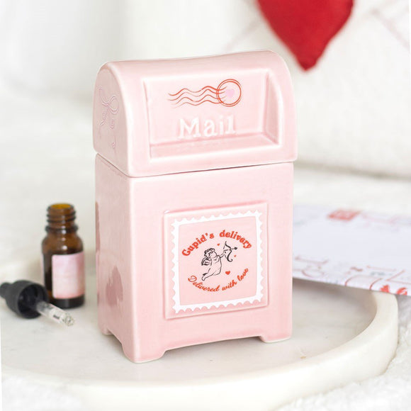 Pink mailbox-shaped container with 'Mail' text, next to a small bottle and dropper on a white surface.