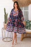 Woman wearing a colorful dress in a home setting with decor elements.