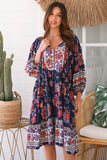 Woman wearing a colorful floral dress in a tropical setting with a cactus plant and woven chair.