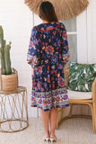 Woman wearing a colorful floral dress in a home setting with a cactus plant and wicker chair.