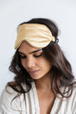 Woman wearing a beige sleep mask against a white background