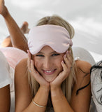 Woman wearing a pink sleep mask with a blurred background