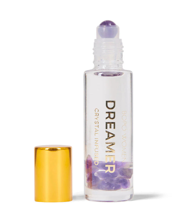 Roll-on bottle labeled 'Dreamer' with a gold cap and purple crystal on a white background
