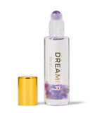 Roll-on bottle labeled 'Dreamer' with a gold cap and purple crystal on a white background